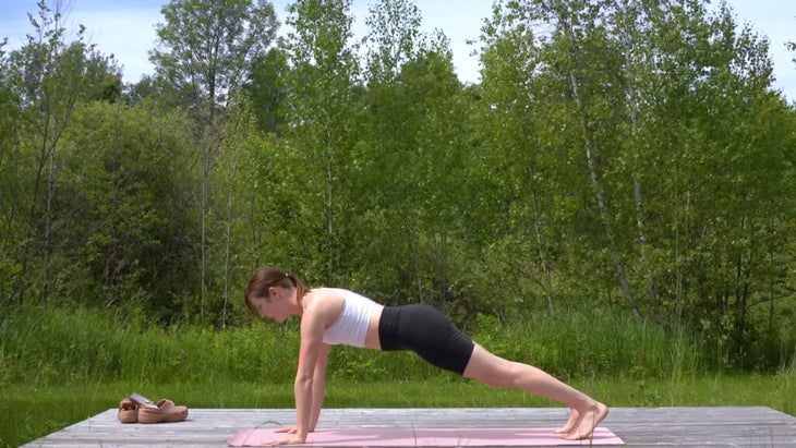 woman outdoors on a yoga mat in a plank position