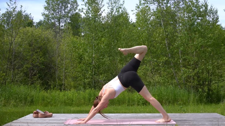 woman outdoors on a yoga mat in scorpion dog pose