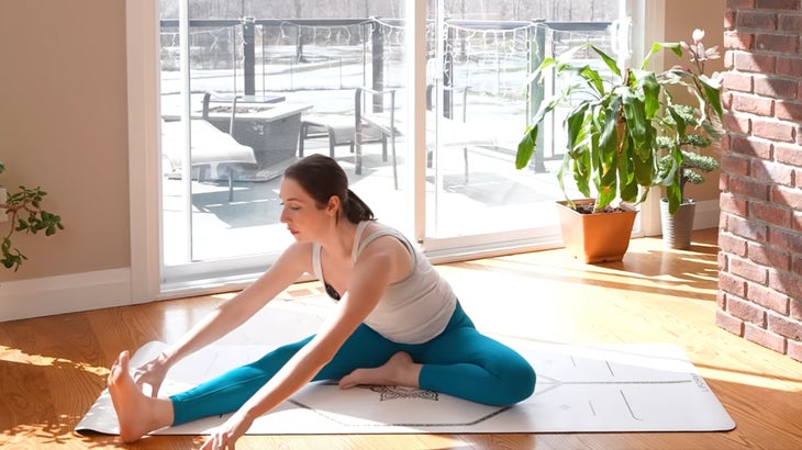 Woman on a yoga mat practicing a 15-minute yoga flow without using her hands