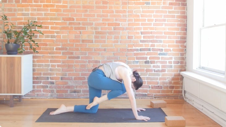 Woman learning how to come from downward dog to a lunge on a yoga mat