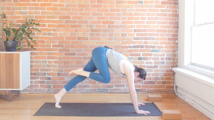 Woman learning how to move from the back of the mat to the front of the mat in a vinyasa yoga setting