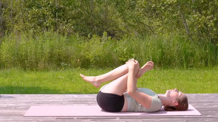 Female doing a calming yoga sequence on a mat aimed at rejuvenating tired legs.