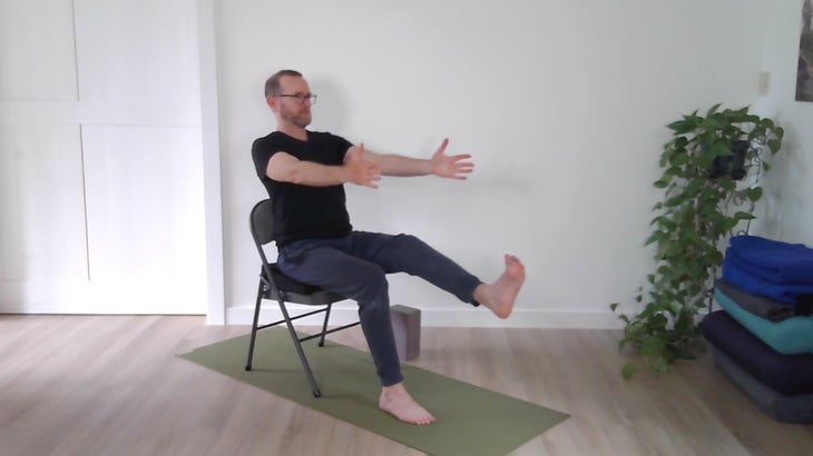 man practicing yoga positions on a chair