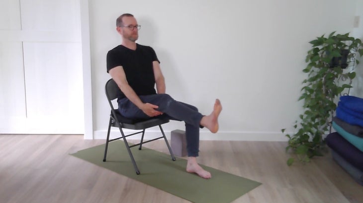 man practicing yoga positions on a chair