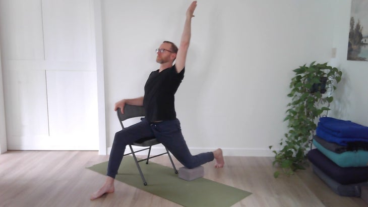 man practicing yoga positions on a chair