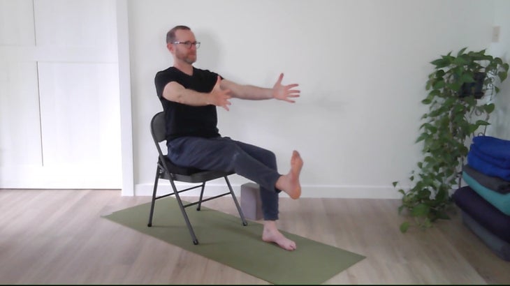 man practicing yoga positions on a chair