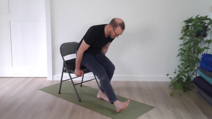 man practicing yoga positions on a chair