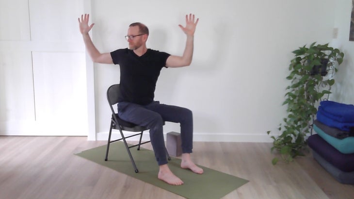 man practicing yoga positions on a chair