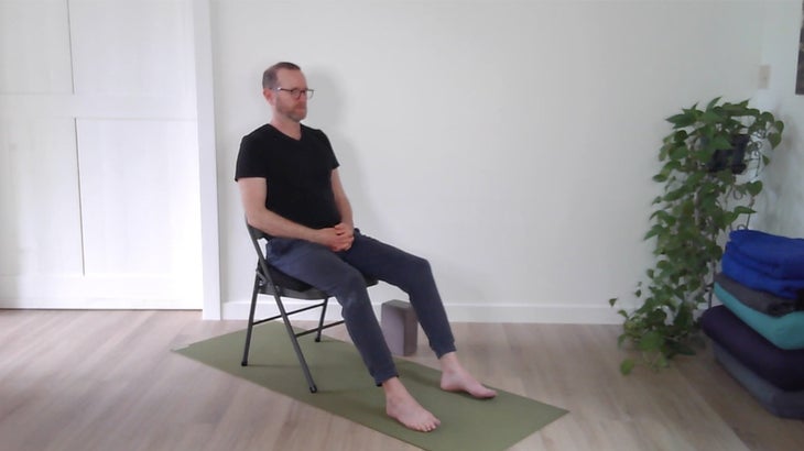 man practicing yoga positions using a chair