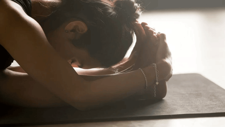 Woman on a yoga mat leaning forward