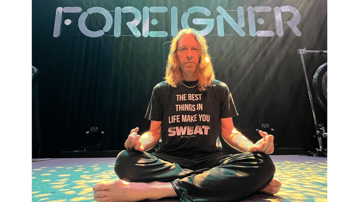 Bassist Jeff Pilson of Foreigner sitting on a stage while meditating