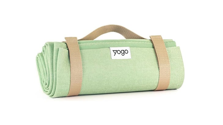 A sage green travel yoga mat rolled up with a carrying strap