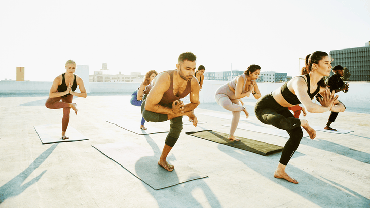 Outdoor yoga class on a rooftop before sunset practicing balancing poses