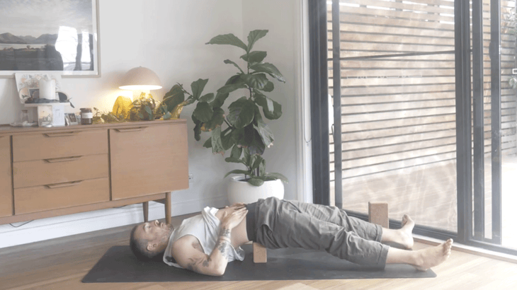 Man lying on his back on a yoga mat with his legs extended while practicing yoga