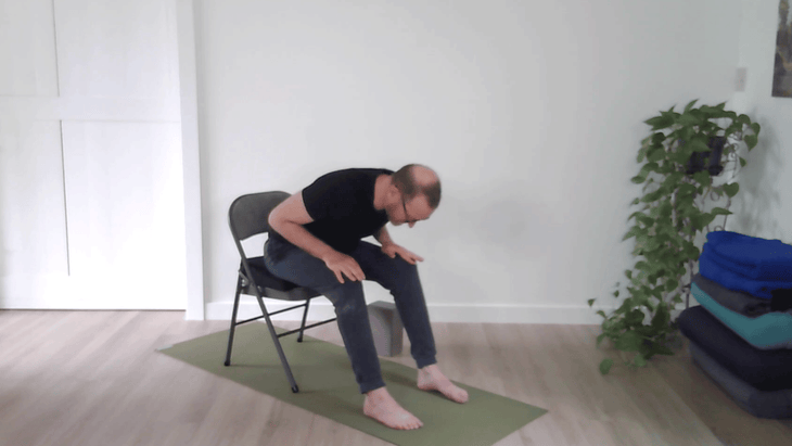 Man practicing Cat Pose in yoga from a chair