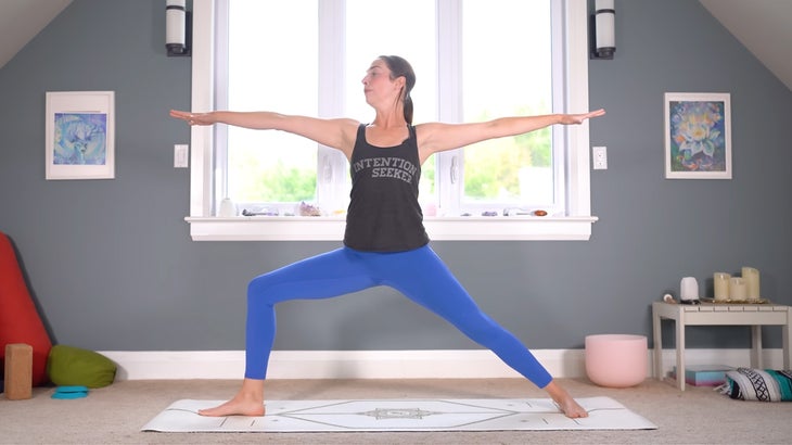 woman practicing warrior pose on a yoga mat