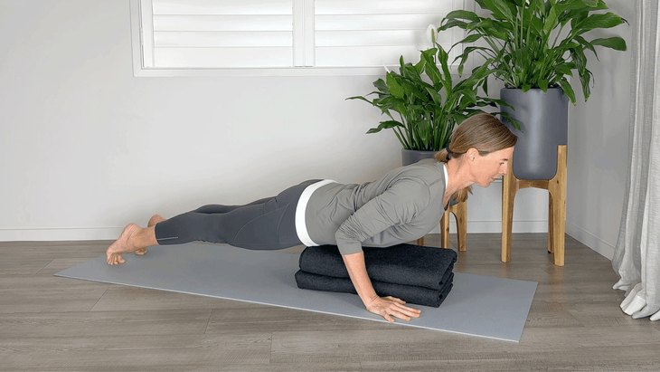 Woman practicing Chaturanga over a bolster