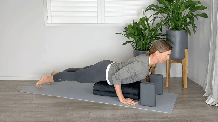 Woman on a yoga mat with blocks beneath her shoulders and a bolster beneath her hips