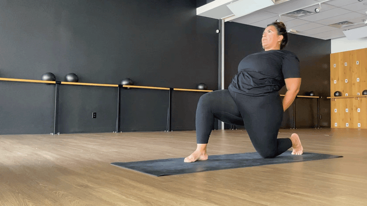 Yoga teacher kneeling on a yoga mat with her arms behind her back