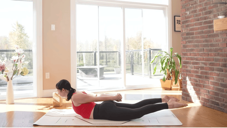 woman on a yoga mat with hands clasped behind her