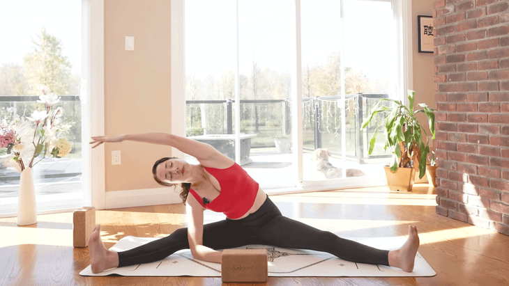 woman in a seated side stretch on a yoga mat