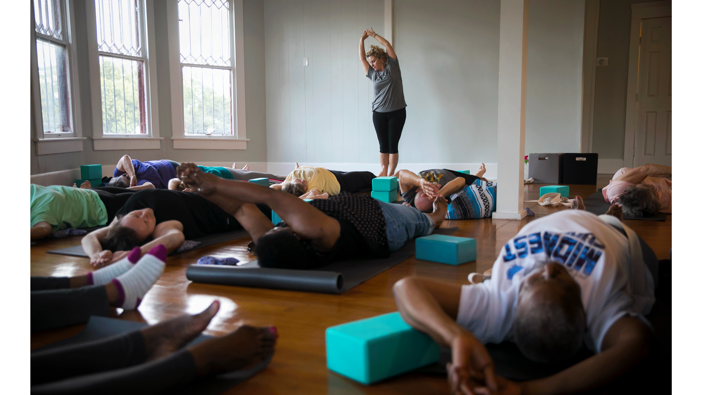Yoga class funded by yoga nonprofits in a house with wood floors and seniors stretching on yoga mats