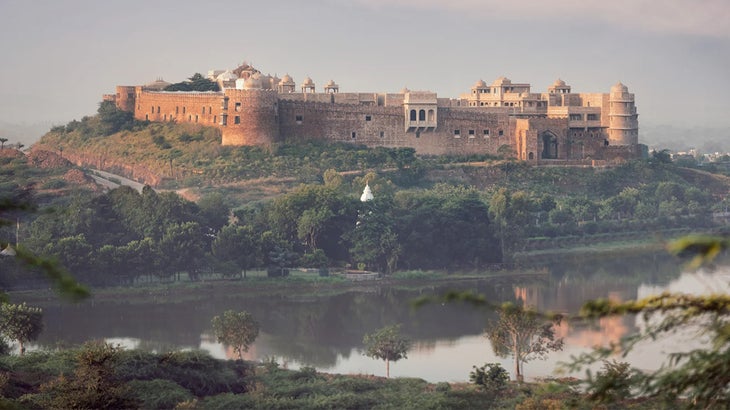 an ancient fort sitting on a bluff in India overlooking a lake