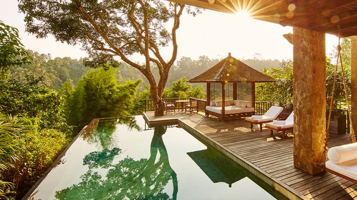 Infinity pool and terrace looking out into the forest in Bali at a yoga retreat destination.