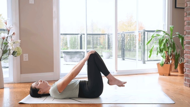 Woman lying on a yoga mat pressing her thighs away from her