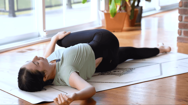 Woman lying on a yoga mat in a reclined twist