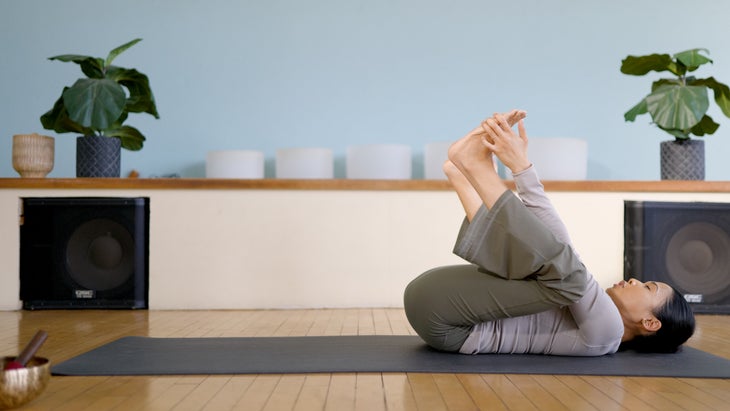 Woman on a yoga mat in reclined Happy Baby