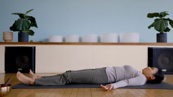 Woman lying on a yoga mat in Savasana