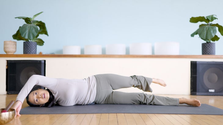 Woman on a yoga mat practicing Scorpion Twist