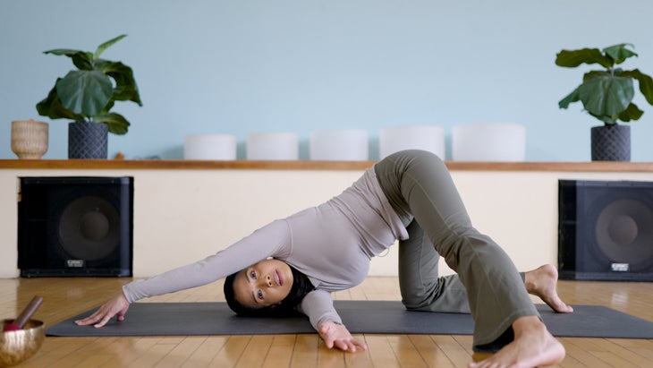 Woman practicing Thread the Needle on a yoga matt