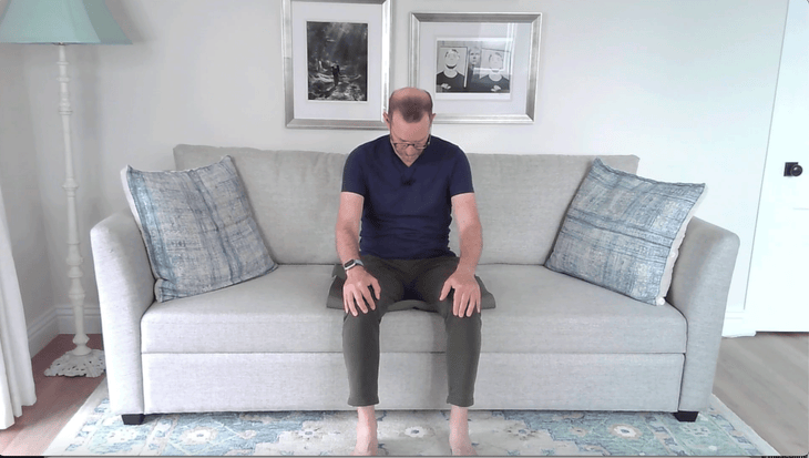 Man doing couch yoga in a seated version of Cow Pose