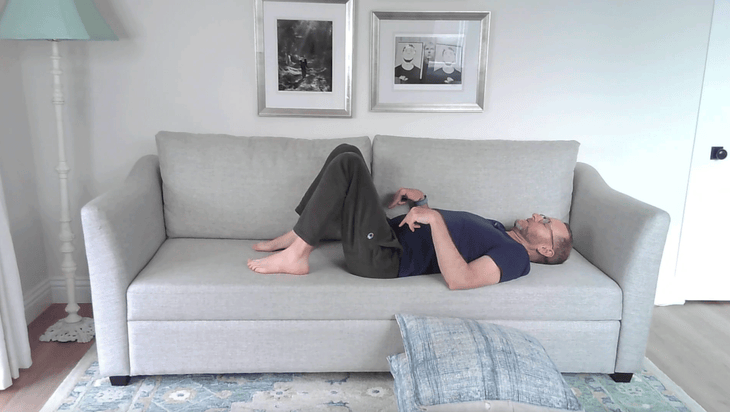 Man reclined on a couch practicing pelvic tilts