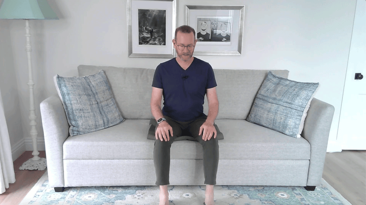 Man sitting on a couch practicing yoga for older adults