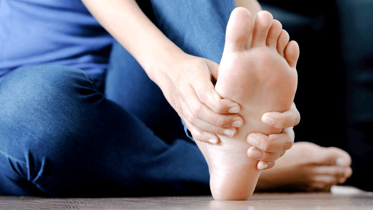 Person sitting on a yoga mat lifting their toes off the mat in a plantar fasciitis stretch