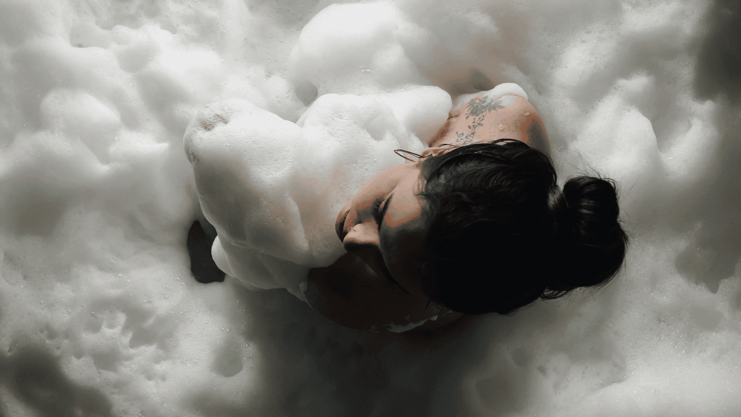 Woman with tattoos in a bubble bath