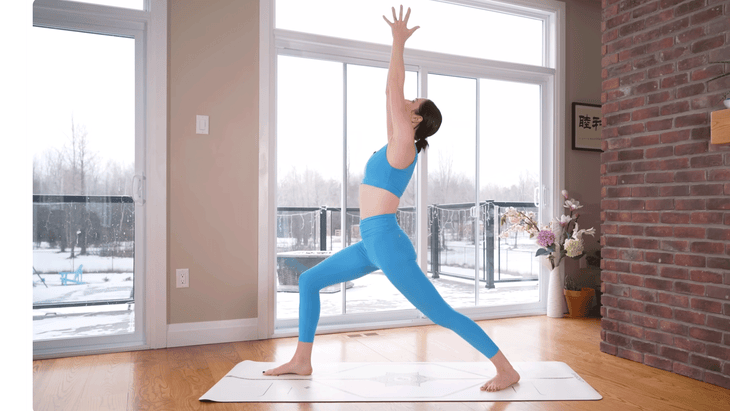 Yoga teacher in Warrior 1 Pose on a mat