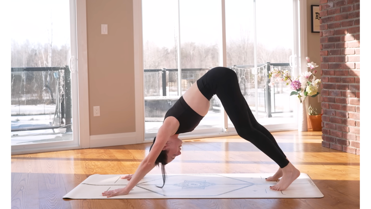 Woman on a yoga mat in Downward-Facing Dog while practicing a 10-minute morning yoga sequence