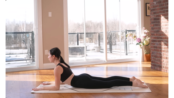 Woman lying on her belly on a yoga mat in Sphinx Pose