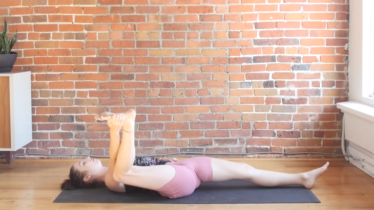 Woman lying on a yoga mat in half happy baby