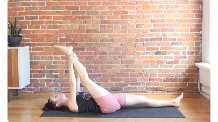 Woman in a hamstring stretch while lying on a yoga mat