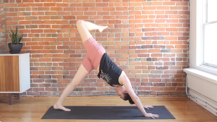 Woman in three-legged Down Dog stretch on a yoga mat