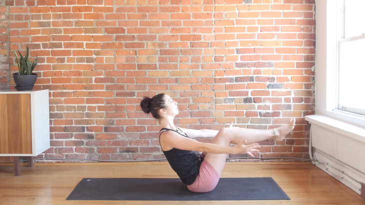 Woman sitting in Boat Pose on a yoga mat