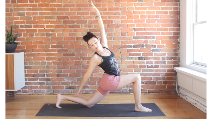 Woman on a yoga mat reaching back in Reverse Lunge