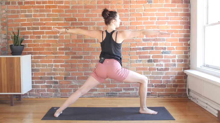 Woman in Warrior 2 on a yoga mat