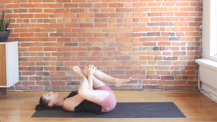 Woman lying on a yoga mat practicing a reclined stretch during a minimal cues yoga class