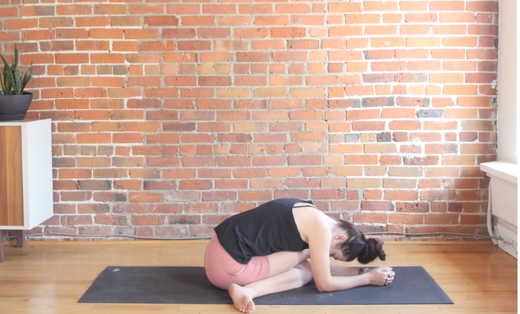 Woman sitting with one leg crossed over the other in Cow Face Pose